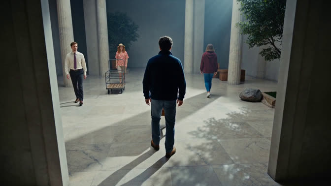 First-frame appearance reference: A person carrying a chair through an office corridor with other people nearby (Indoor; third person view)